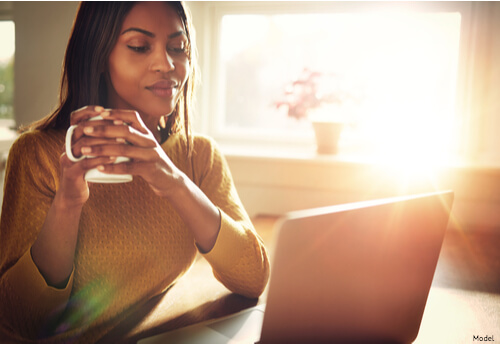 Woman having coffee in front of computer