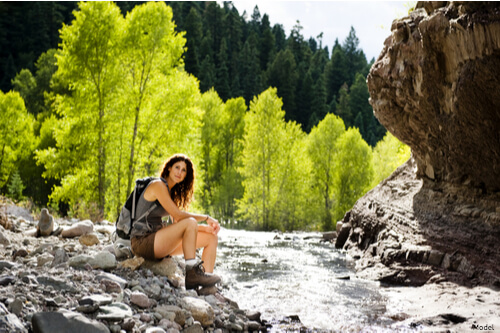 Woman sitting on rocks next to a river