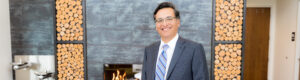 Dr. Aguirre in front of modern fireplace with wood accents