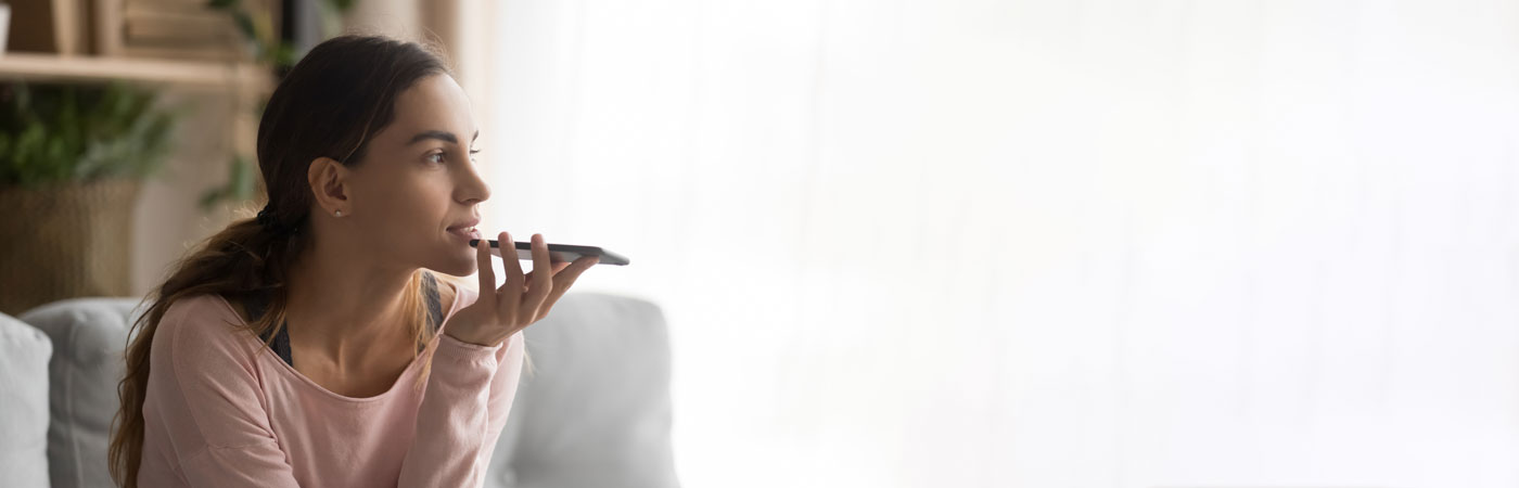 Woman holding smartphone using virtual assistant or talk on speakerphone