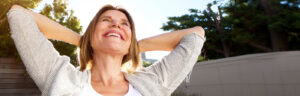 Happy older woman smiling with hands behind head